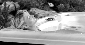 woman laying in corner seat of hot tub with her eyes closed