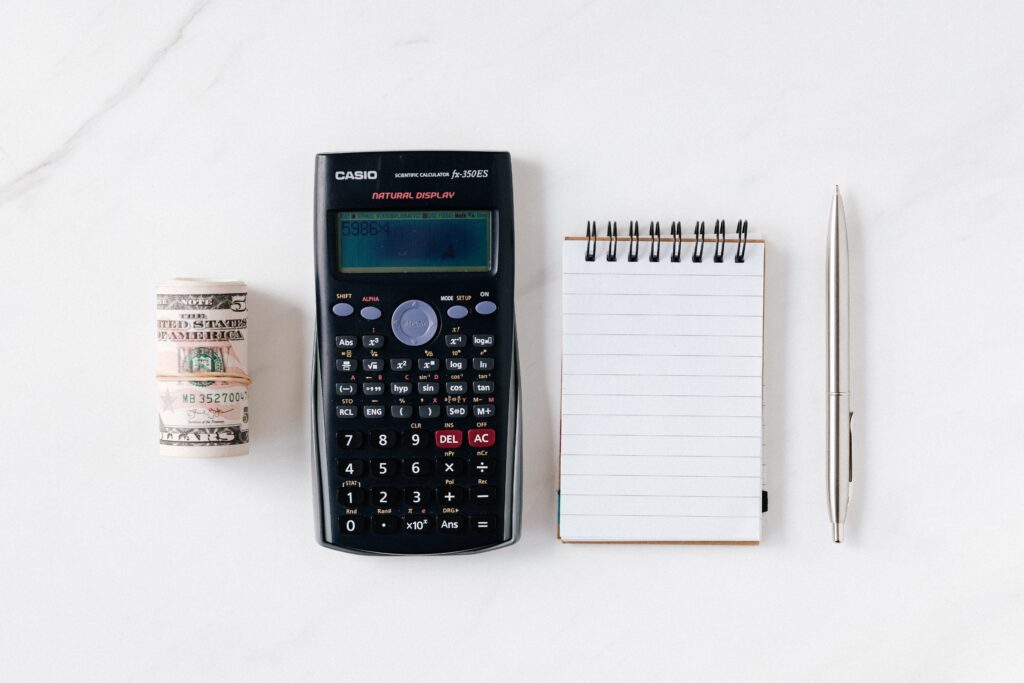 wad of money, calculator, notepad, and pen lined up