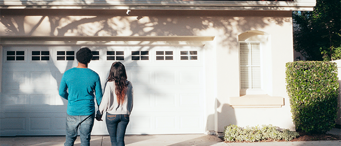 Homeowners holding hands in front of their new house